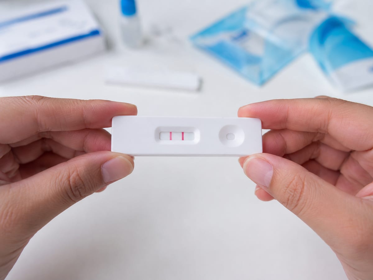 Teste rápido de Covid-19 com resultado positivo segurado por mãos
