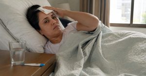 Mulher com dengue deitada na cama com compressa na testa em Campinas